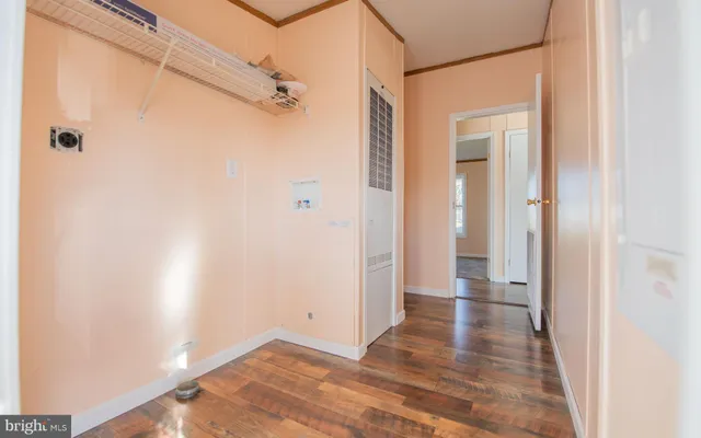 a view of a hallway with wooden floor and a bathroom
