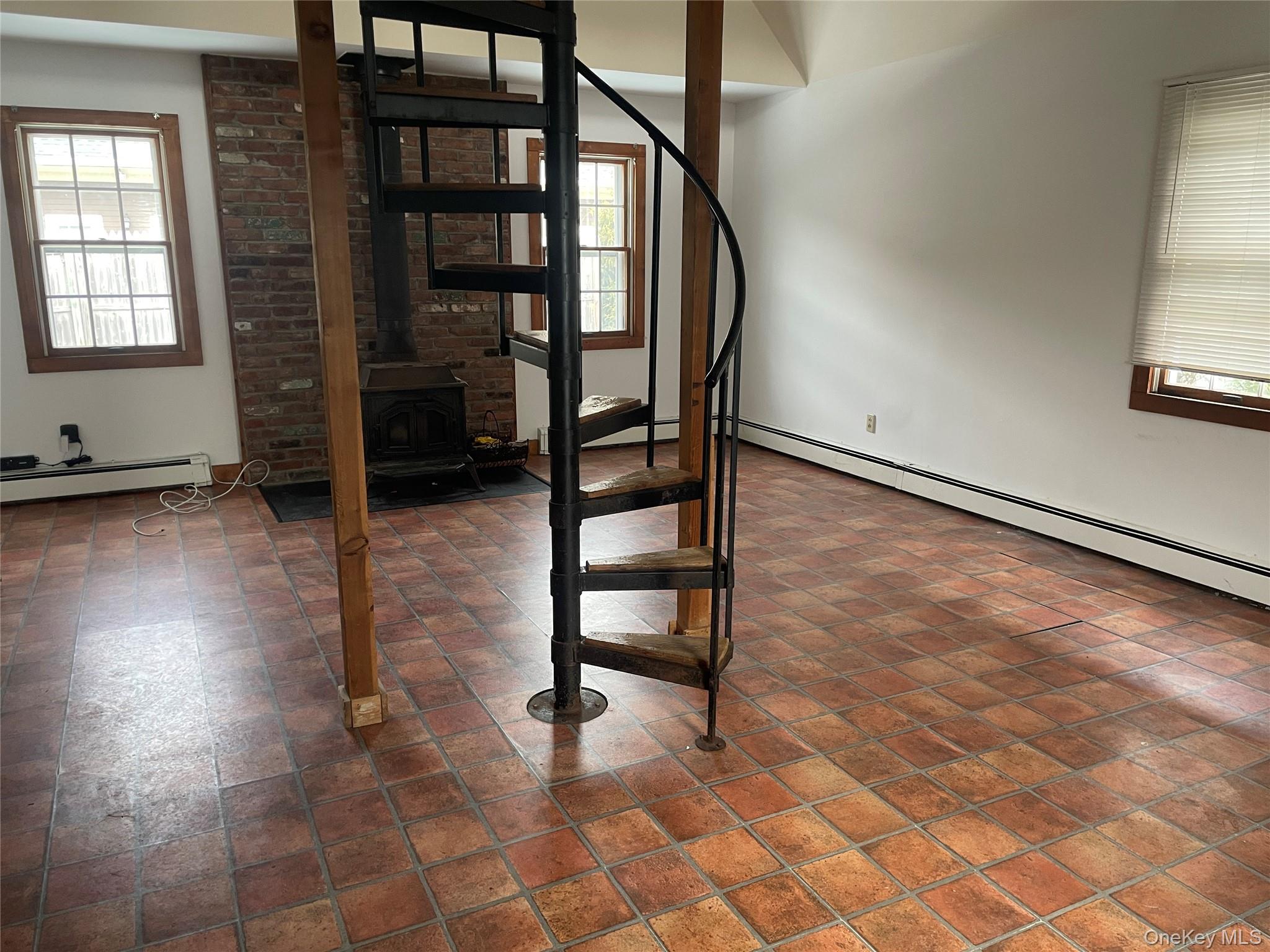 150 Bedford Road Armonk, NY 10504 - Photo 10 of 15 Stairs featuring a wood stove, plenty of natural light, and a baseboard radiator