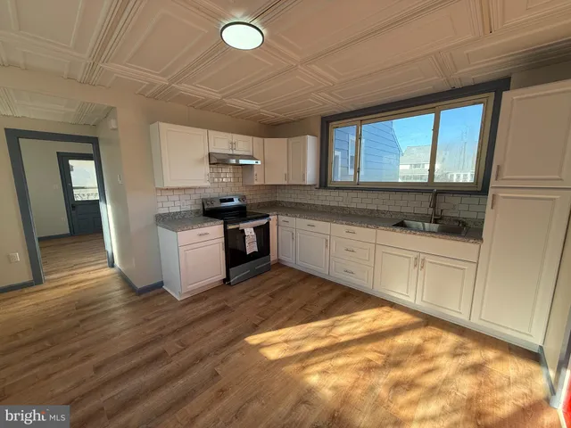 a kitchen with granite countertop a stove a sink and a microwave