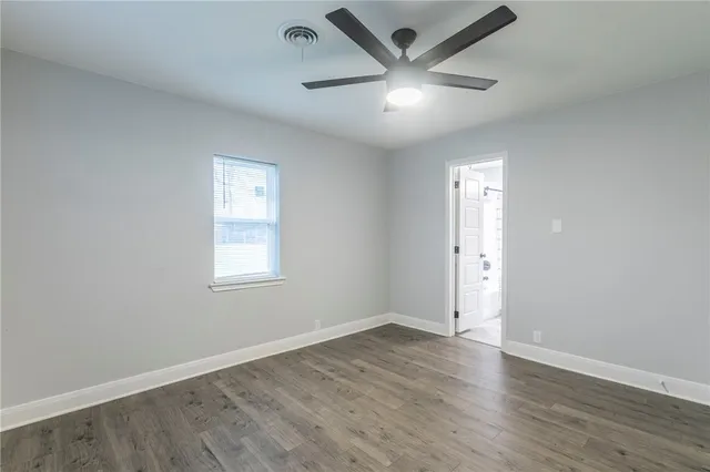 an empty room with wooden floor ceiling fan and windows