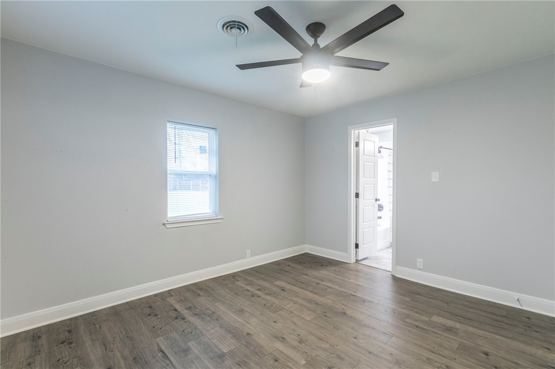 105 Alamo Drive McGregor, TX 76657 - Photo 18 of 34 an empty room with wooden floor ceiling fan and windows