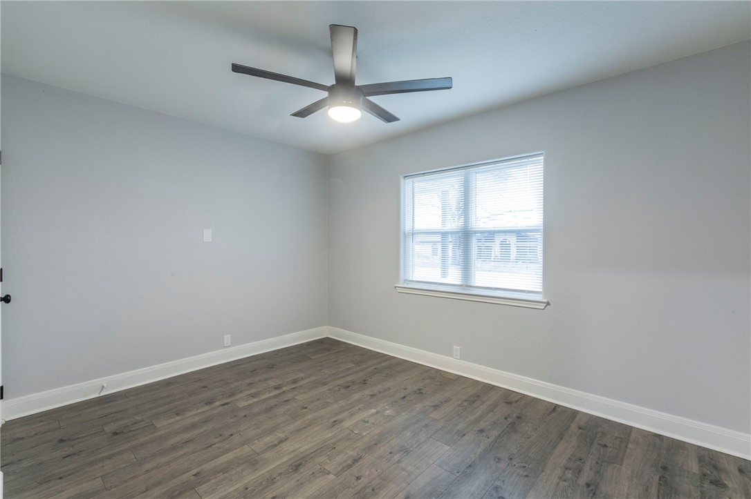 105 Alamo Drive McGregor, TX 76657 - Photo 24 of 34 an empty room with wooden floor ceiling fan and windows
