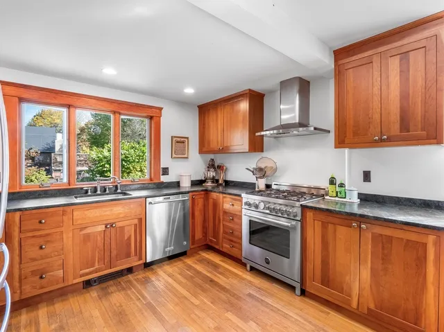 a kitchen with stainless steel appliances granite countertop a refrigerator a sink dishwasher a stove and white countertops with wooden floor