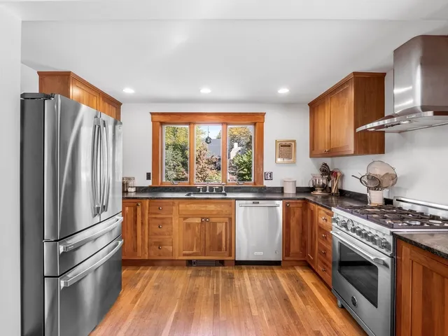 a kitchen with granite countertop stainless steel appliances a refrigerator cabinets and wooden floor