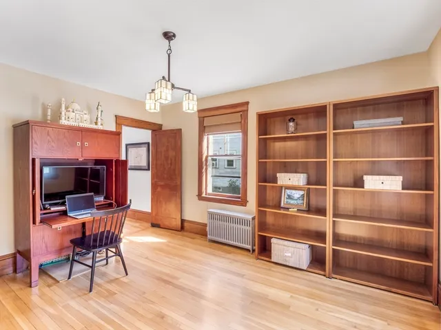 a view of an empty room with a window and wooden floor