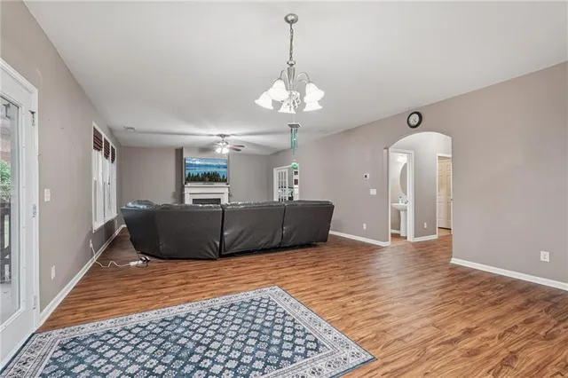 a open kitchen with stainless steel appliances kitchen island granite countertop a refrigerator a stove top oven a sink dishwasher and wooden cabinets with wooden floor