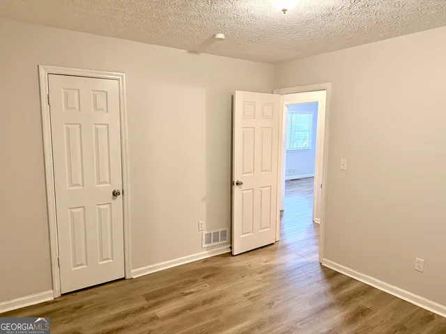 an empty room with wooden floor & closet area