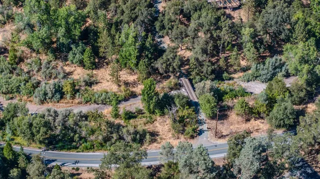 an aerial view of residential house with outdoor space and trees all around