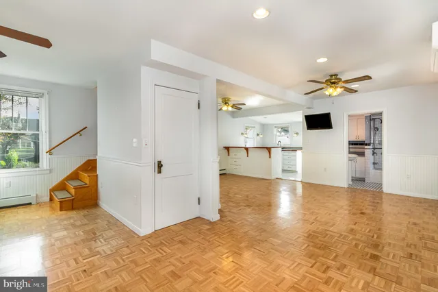 a view of an empty room and kitchen view with a ceiling fan