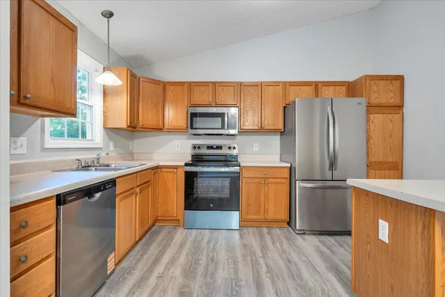 a kitchen with granite countertop wooden floors stainless steel appliances and a window