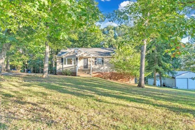 a view of a house with a big yard and large trees