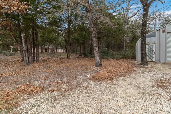 a backyard of a house with lots of plants and large trees
