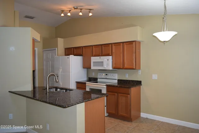 a kitchen with granite countertop a sink a stove and refrigerator