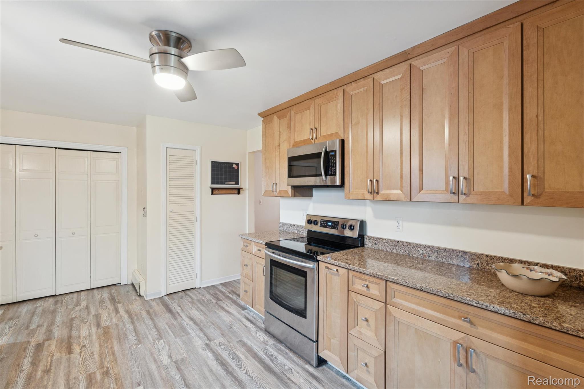 3031 Cedar Point Howell, MI 48843 - Photo 15 of 51 Kitchen featuring appliances with stainless steel finishes, light stone countertops, light wood-type flooring, ceiling fan, and light brown cabinets