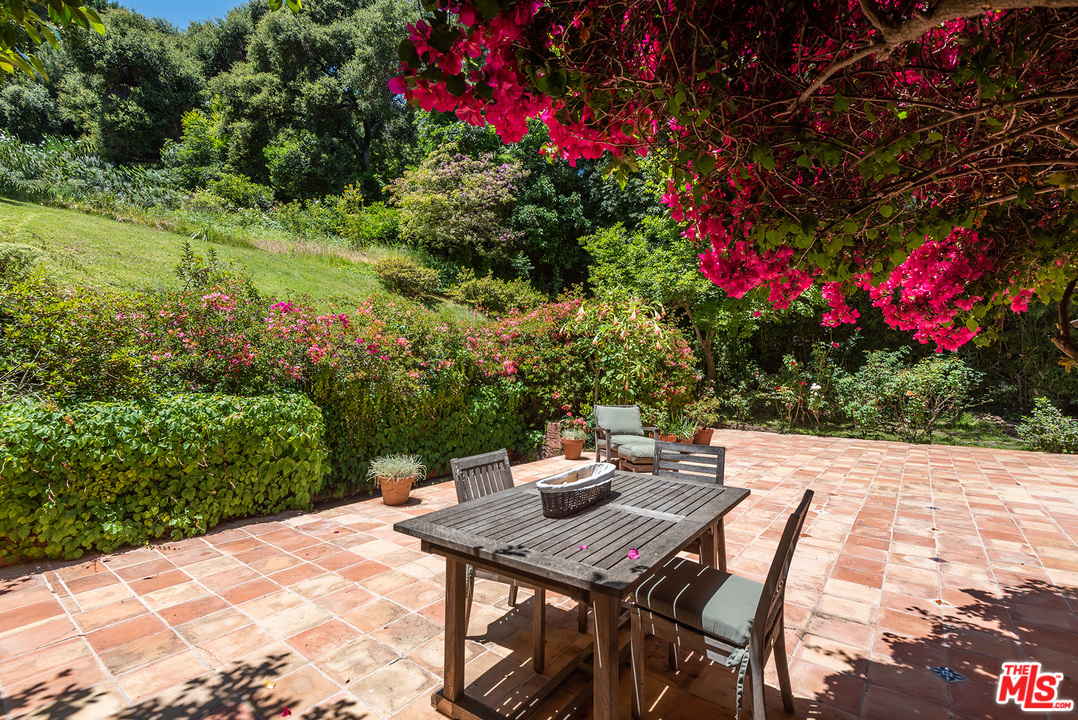 1491 Stone Canyon Road Los Angeles, CA 90077 - Photo 15 of 27 a view of a backyard with table and chairs and potted plants
