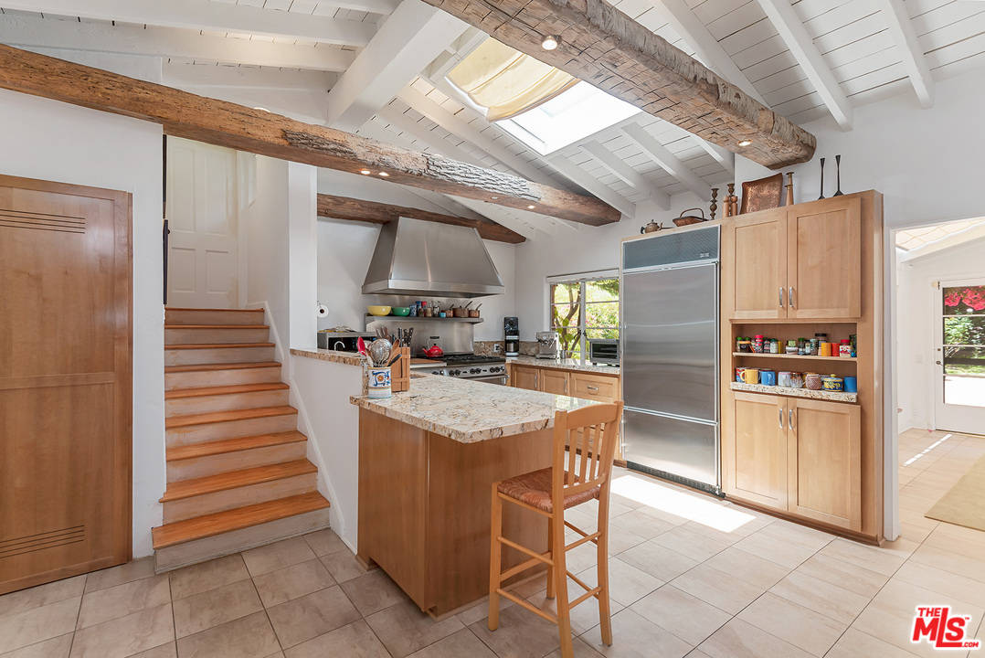 1491 Stone Canyon Road Los Angeles, CA 90077 - Photo 7 of 27 a kitchen with stainless steel appliances kitchen island granite countertop lots of counter top space and cabinets