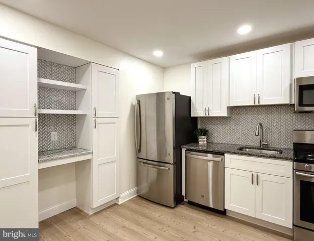 a kitchen with white cabinets and refrigerator