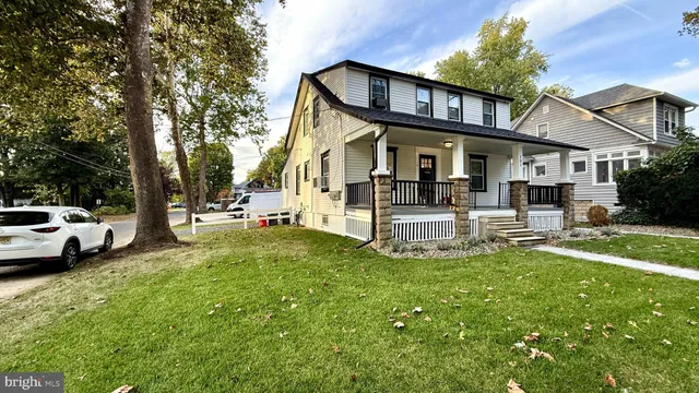 a view of a white house with a big yard and large trees