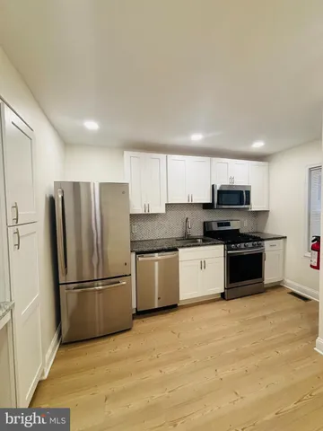 a kitchen with granite countertop a refrigerator and a stove top oven