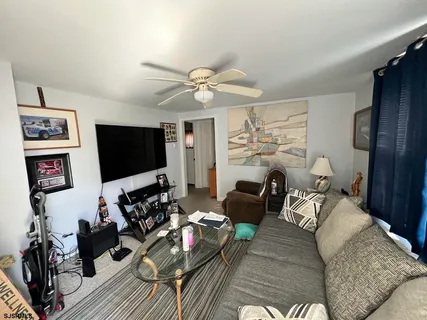a living room with furniture ceiling fan and a flat screen tv