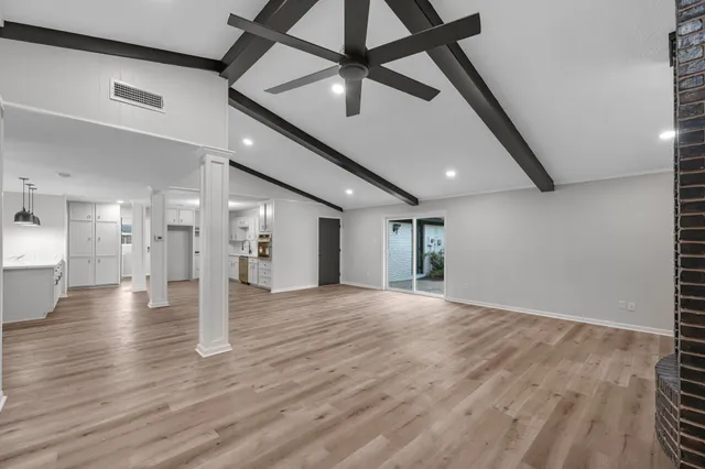 a view of an empty room with wooden floor and a ceiling fan