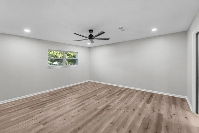an empty room with wooden floor and windows