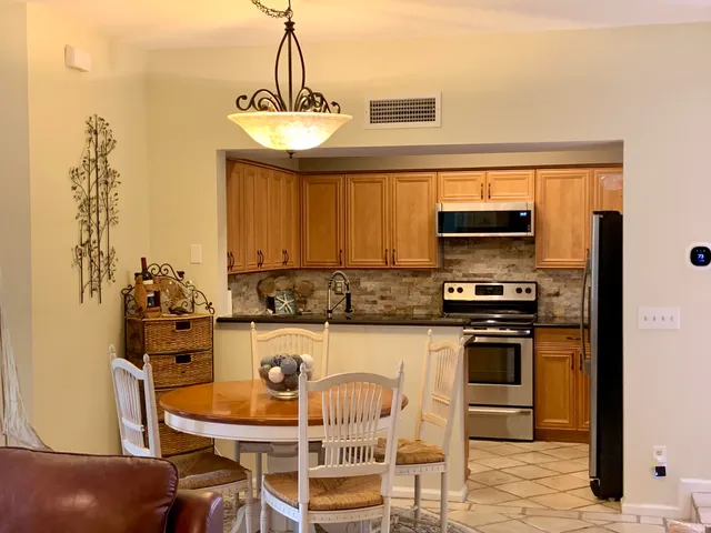 a kitchen with stainless steel appliances granite countertop a stove top oven a sink a dining table and chairs with wooden floor