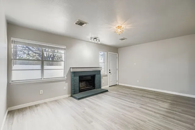 an empty room with windows fireplace and fans