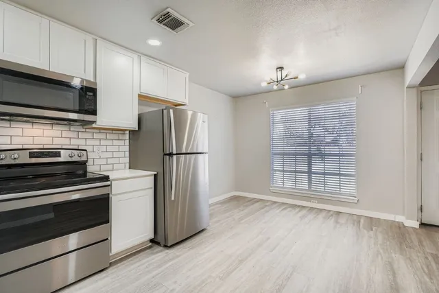 a kitchen with a refrigerator stove and wooden cabinets