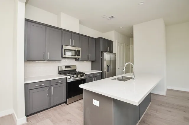 a kitchen with stainless steel appliances a sink stove refrigerator and cabinets