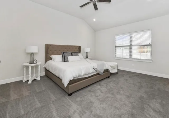 a bed sitting in a spacious bedroom next to a window and a lamp