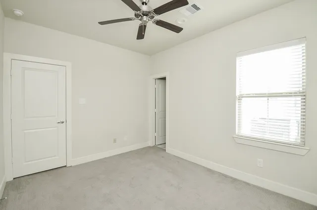 an empty room with a window and a fan