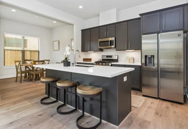 a kitchen with stainless steel appliances granite countertop a sink a stove a refrigerator cabinets and dining table