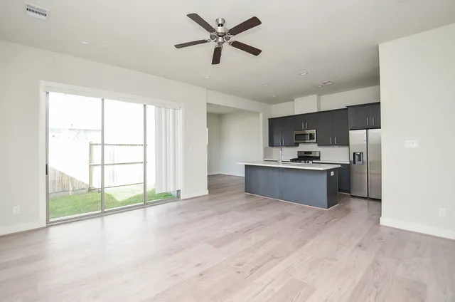 a large kitchen with stainless steel appliances a large counter top a sink and a refrigerator