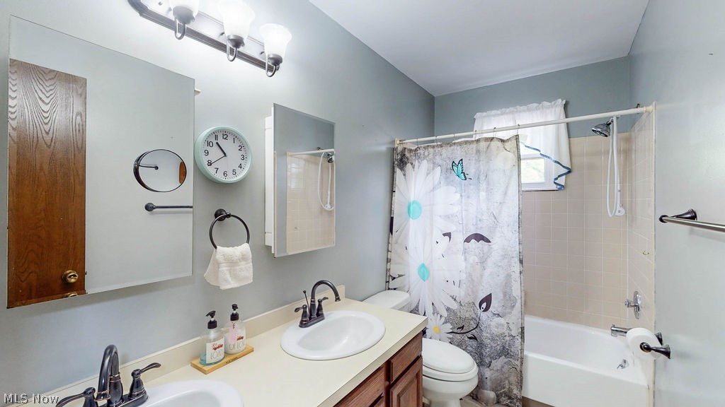 38667 Chestnut Ridge Road Elyria, OH 44035 - Photo 13 of 35 Bathroom featuring a dual vanity with undermount sinks, neutral countertops, and dark wood-finish cabinetry