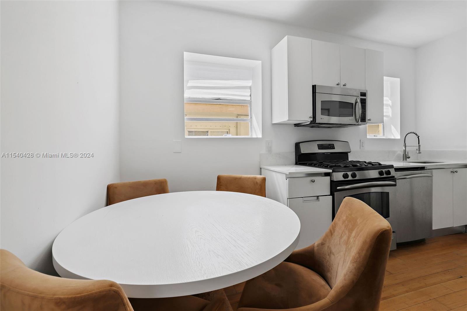 4812 Pine Tree Drive, Unit 207 Miami Beach, FL 33140 - Photo 4 of 23 a kitchen with stainless steel appliances a stove a sink a microwave and dining table