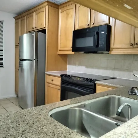 a kitchen with stainless steel appliances granite countertop a refrigerator a stove and a sink with wooden floor