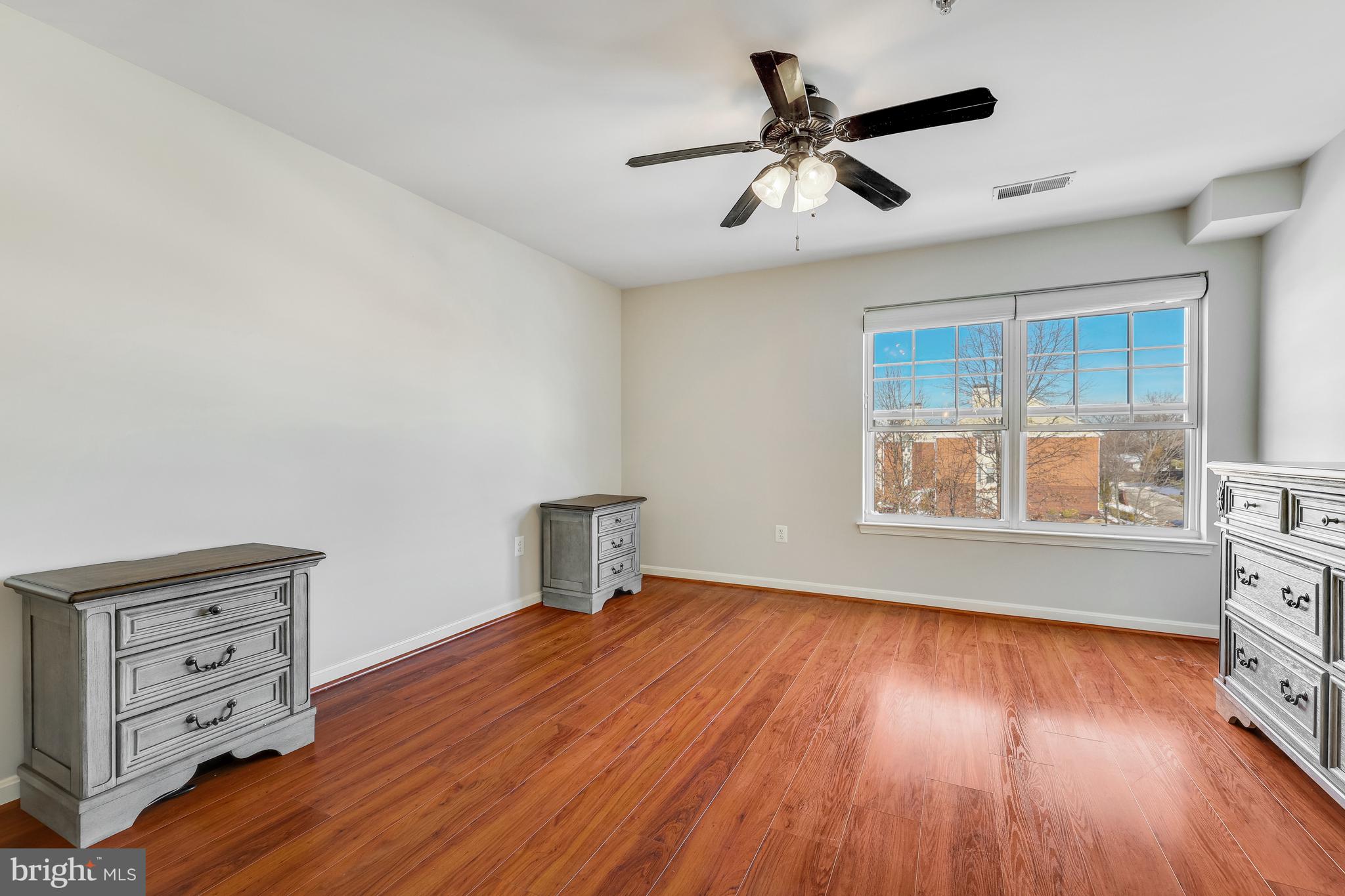 521 Constellation Square Southeast, Unit J Leesburg, VA 20175 - Photo 19 of 37 a view of an empty room with a window and wooden floor