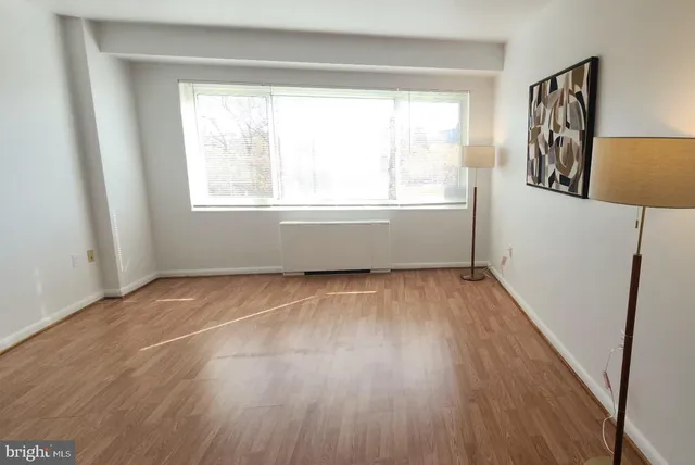 a view of an empty room with wooden floor and a window