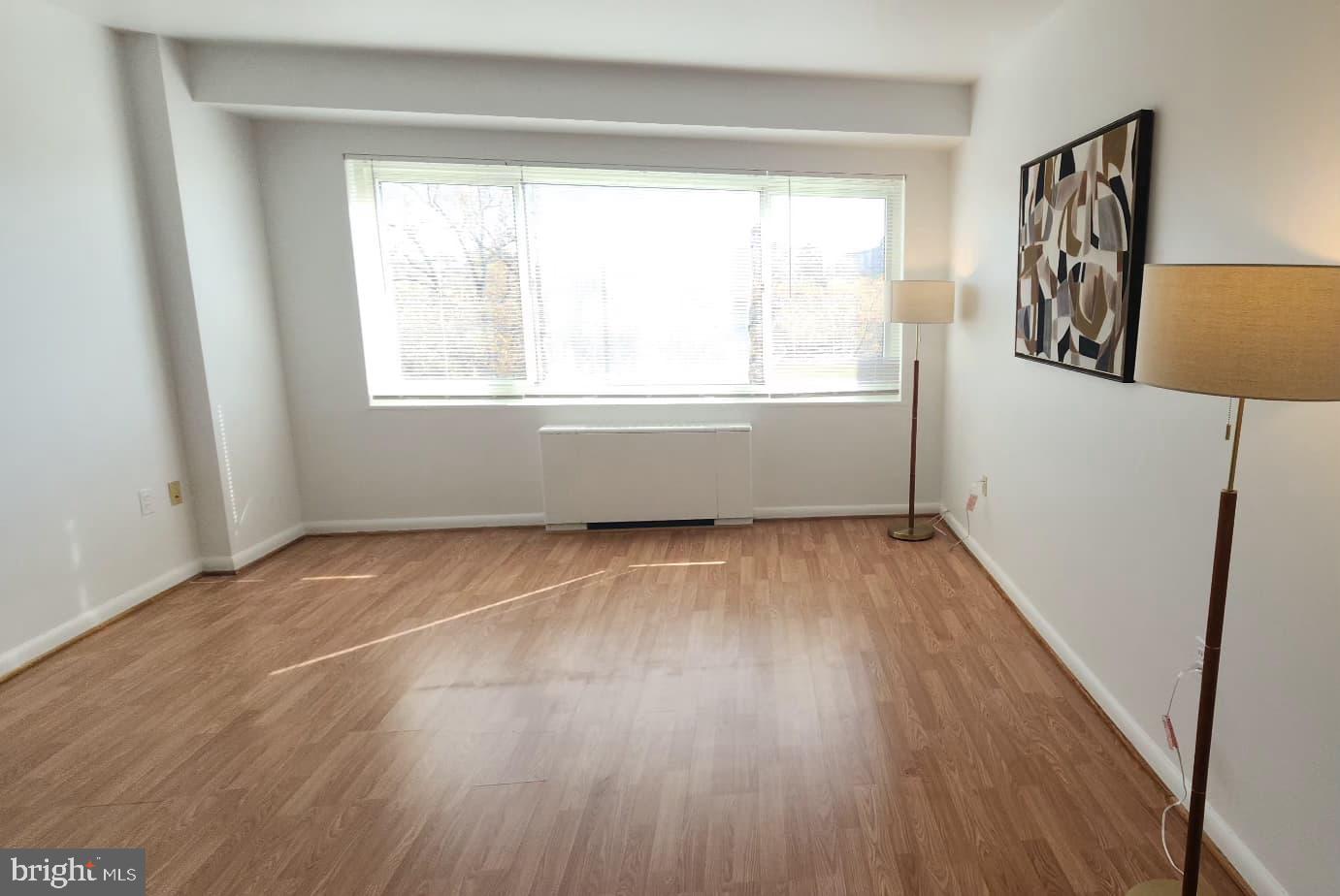 4201 Cathedral Avenue Northwest, Unit 1012E Washington, DC 20016 - Photo 1 of 18 a view of an empty room with wooden floor and a window