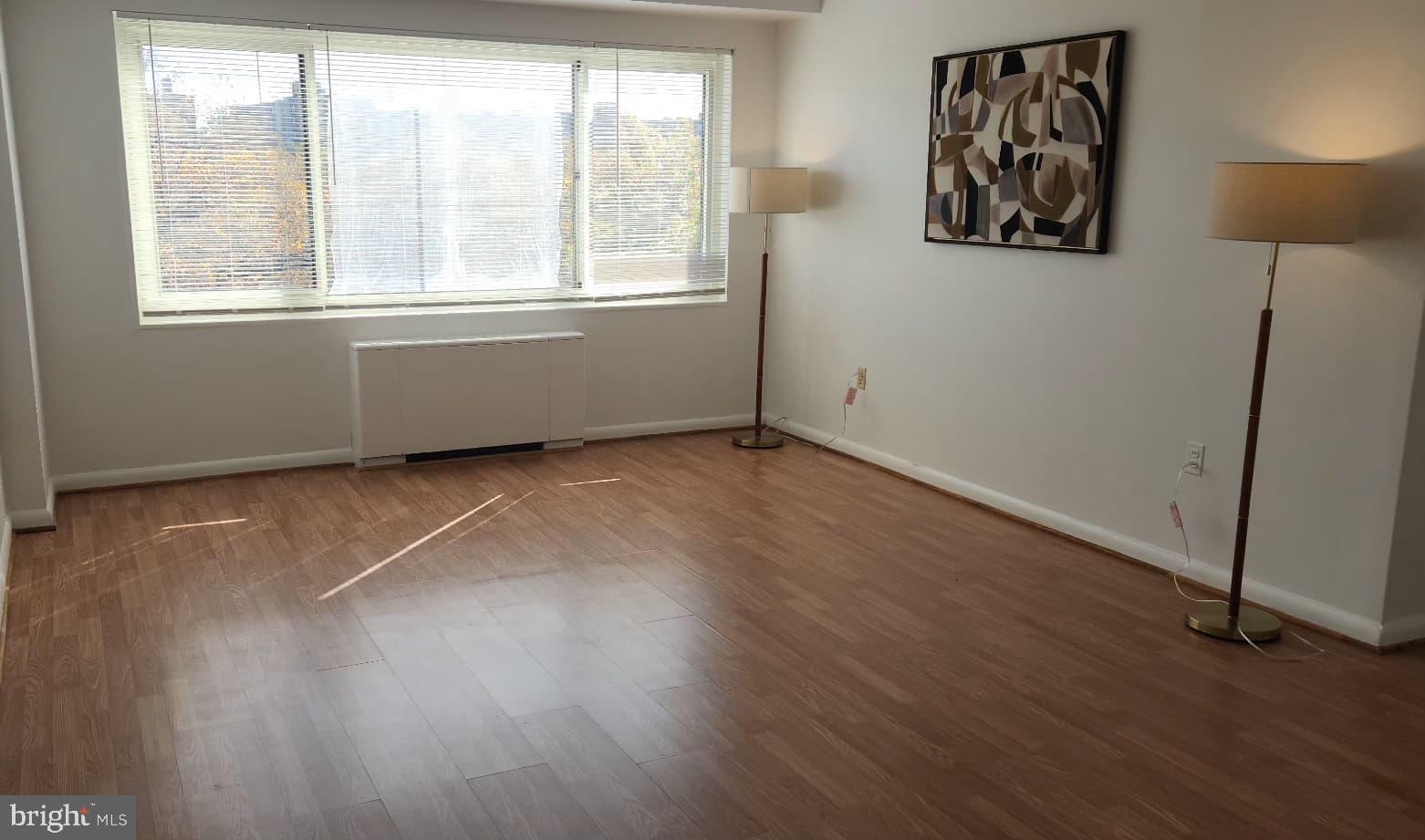 4201 Cathedral Avenue Northwest, Unit 1012E Washington, DC 20016 - Photo 2 of 18 an empty room with wooden floor and windows
