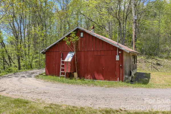 a view of a barn in the backyard with large trees