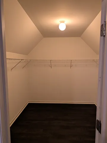 a view of an empty room with wooden floor and a ceiling fan