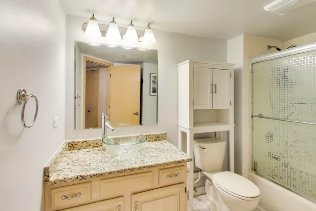 a bathroom with a granite countertop sink toilet and shower