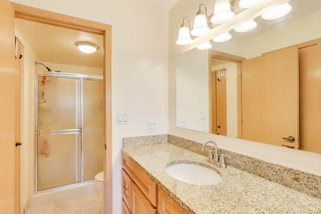 a bathroom with a granite countertop sink a mirror and a shower