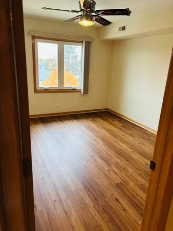 a view of an empty room with a window and wooden floor