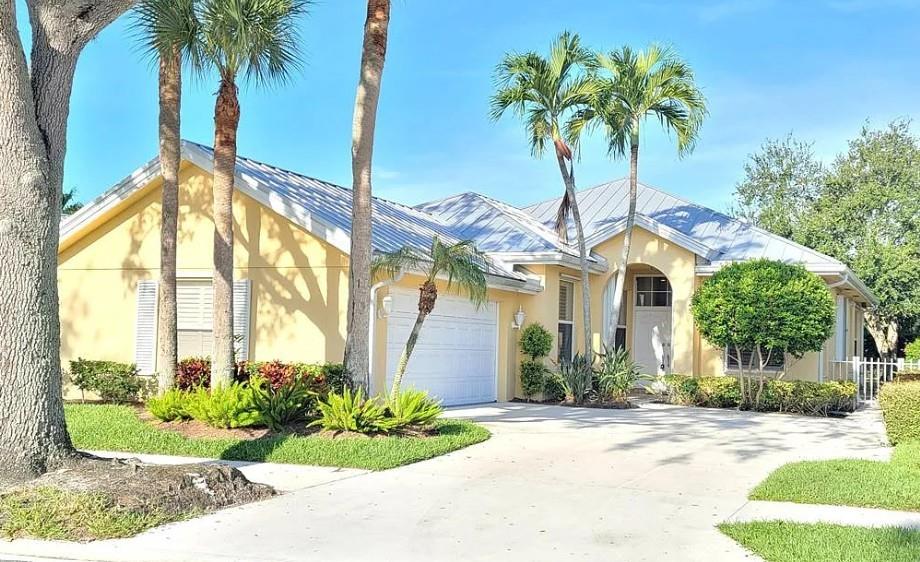 a front view of yellow house with a garden