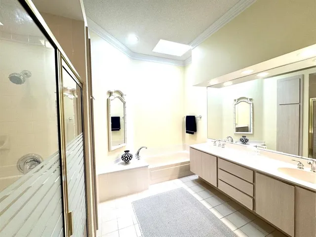 a bathroom with a double vanity sink a large mirror and bathtub