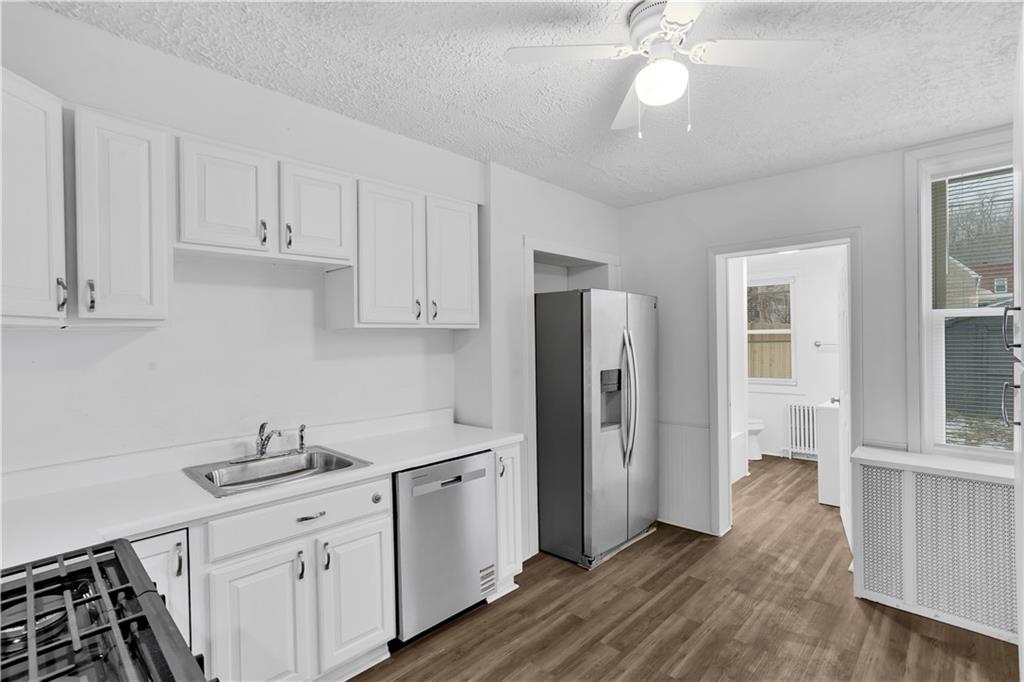 1841 Chislett Street Pittsburgh, PA 15206 - Photo 12 of 28 a kitchen with stainless steel appliances a sink cabinets and wooden floor
