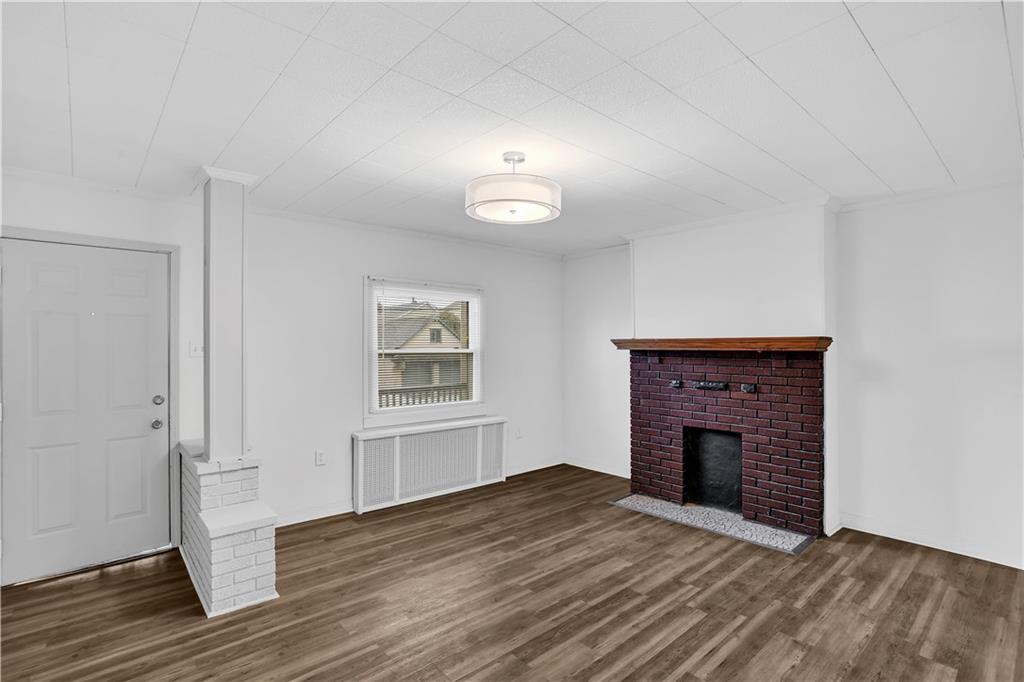 1841 Chislett Street Pittsburgh, PA 15206 - Photo 5 of 28 an empty room with wooden floor a fireplace and windows